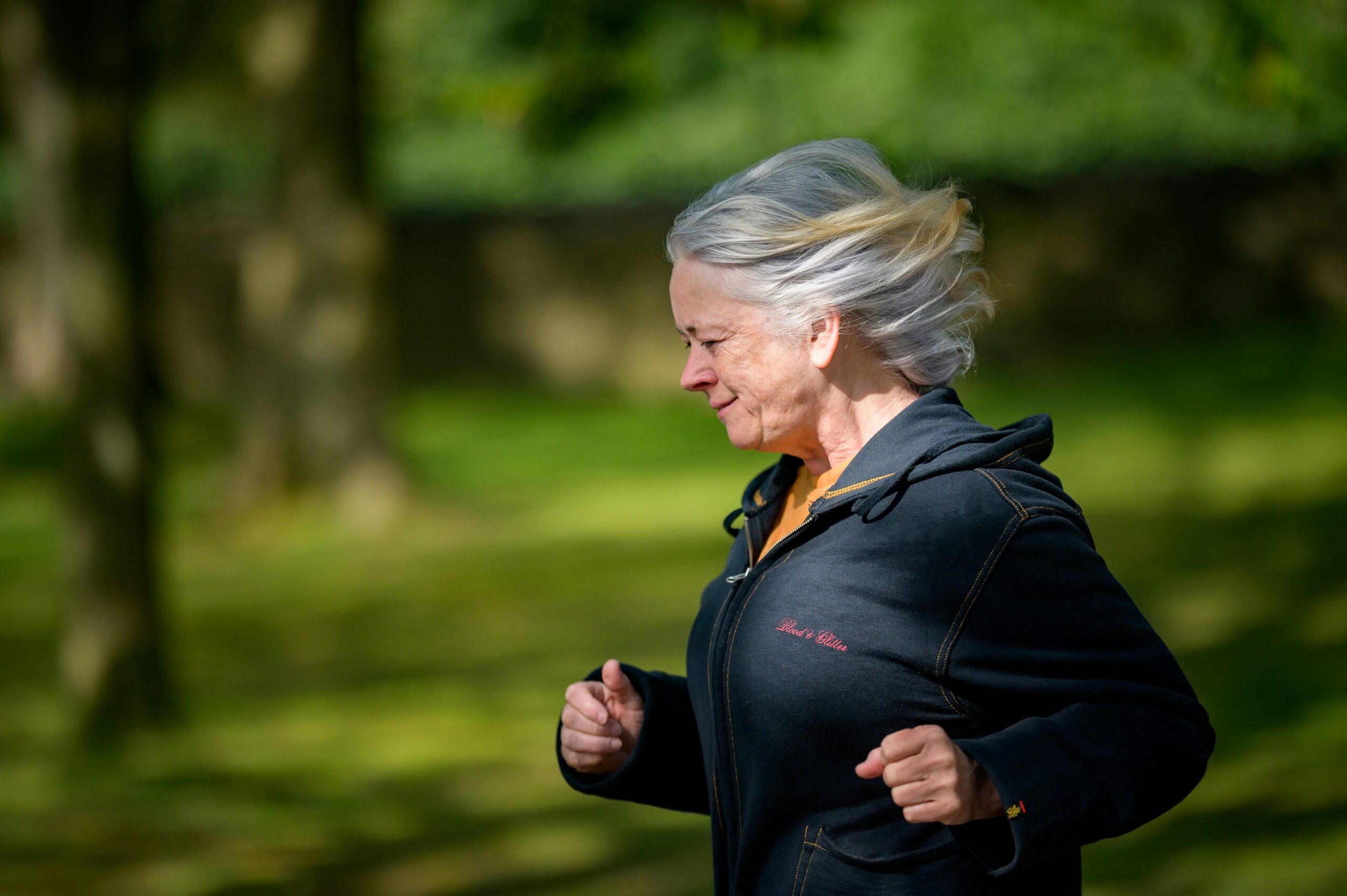 Smiling woman in her 50s running outdoors, keeping energy after 45.